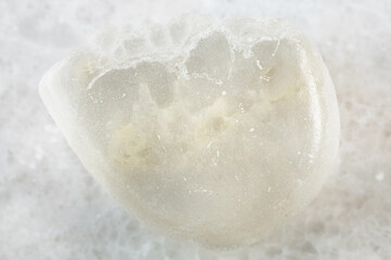 closeup of sample of natural mineral from geological collection - polished Ulexite (TV rock) stone on white marble background from California, USA