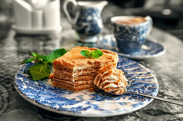 Layered piece of honey cake on an antique plate. Close-up of a delicious honey cake with mint
