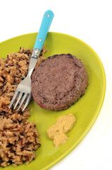 Steak haché de boeuf avec du riz pilaf et de la moutarde servis dans une assiette sur fond blanc