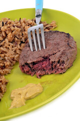 Steak haché de boeuf avec du riz pilaf et de la moutarde servis dans une assiette sur fond blanc