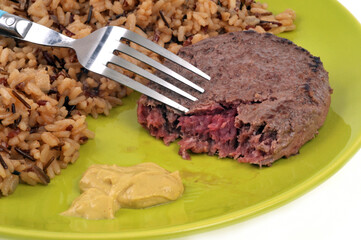 Steak haché de boeuf avec du riz pilaf et de la moutarde servis dans une assiette sur fond blanc