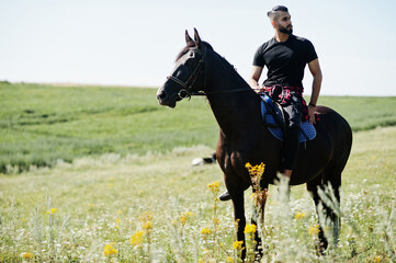 Arab tall beard man wear in black ride arabian horse.