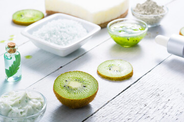 beauty products with kiwi fruit ingredient on white wooden table