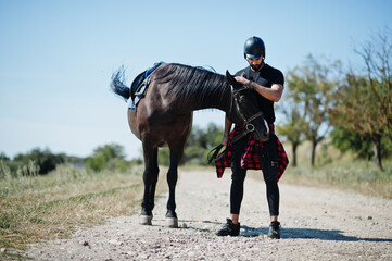 Arab tall beard man wear in black helmet with arabian horse.