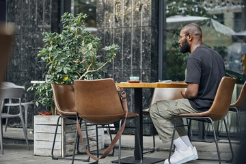 Young bearded male person sitting in cafe