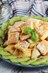 Austrian dessert Kaiserschmarrn served with sugar powder and kiwi fruit