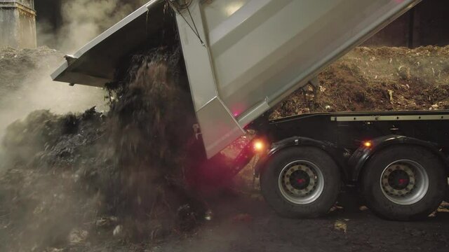 Parallax shot of a big garbage truck dumping organic waste in a compost plant.