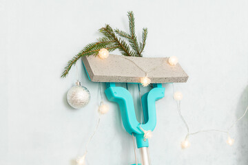 Mop above wall decorated with Christmas lights and fir branches.