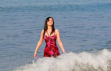 Fototapeta premium Young smiling woman standing in sea waves