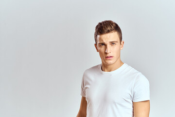 Handsome man in a white T-shirt on a light background close-up portrait cropped view