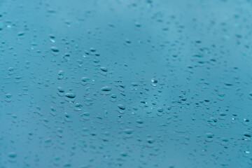 Raindrop on car window glass in morning rainy season for background or wallpaper. Drop of water on glass with blue sky and clouds.