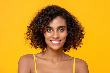 Happy smiling beautiful African American woman looking at camera isolated on colorful yellow background