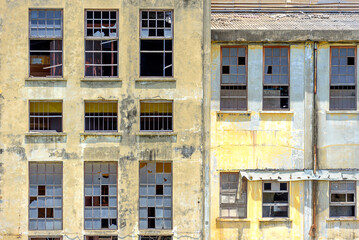 Window pattern of an old and derelict building with shattered windowpanes.