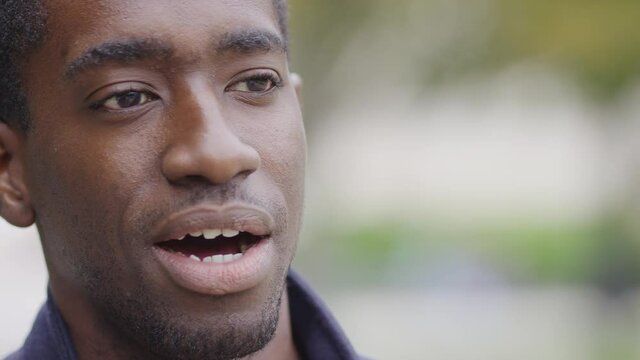 Close up portrait of black male being giving opinions whilst interviewed outdoors 