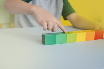 close up of children's hands counting colored blocks in lines on the table