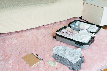 Young Pregnant woman packing suitcase for maternity hospital at home, closeup. Checklist for childbirth. Pregnancy during coronavirus covid-19 pandemic