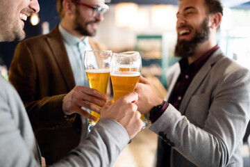 Happy young business men talking and drinking beer in a pub