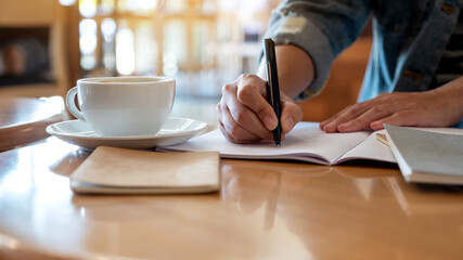 Closeup image of a woman writing on a notebook on the table