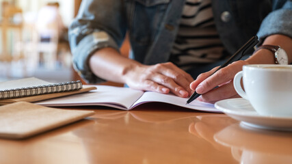 Closeup image of a woman writing on a notebook on the table