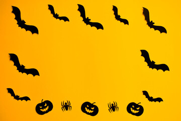Frame of paper silhouettes of bats, scary pumpkins and spiders on orange background. Treat or trick Halloween holiday banner template with copy space in the middle.