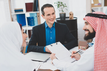 Arab man signs a document at a realtor in office.