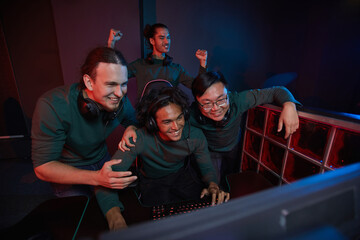 Group of excited gamers happy their victory in computer game they looking at computer monitor and smiling during their playing