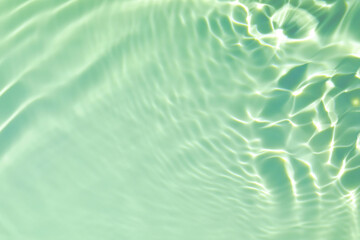 De-focused closeup of mint green transparent clear calm water surface texture with splashes and...
