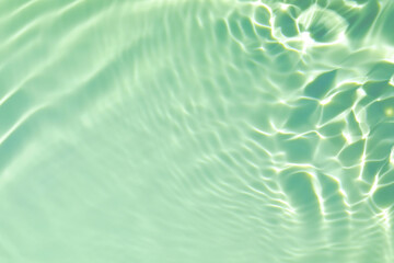 De-focused closeup of mint green transparent clear calm water surface texture with splashes and bubbles. Trendy abstract summer nature background. Mint colored waves in sunlight with copy space.
