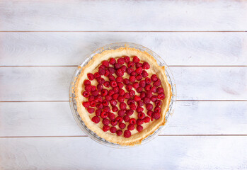 Preparation of shortbread pie with raspberries on white wooden background, top view