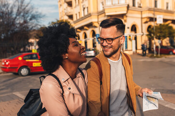 Fototapeta premium Smiling couple enjoying on vacation, young tourist having fun walking and exploring city street during the day. 