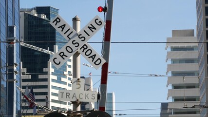 Level crossing warning signal in USA. Crossbuck notice and red traffic light on rail road intersection in California. Railway transportation safety symbol. Caution sign about hazard and train track
