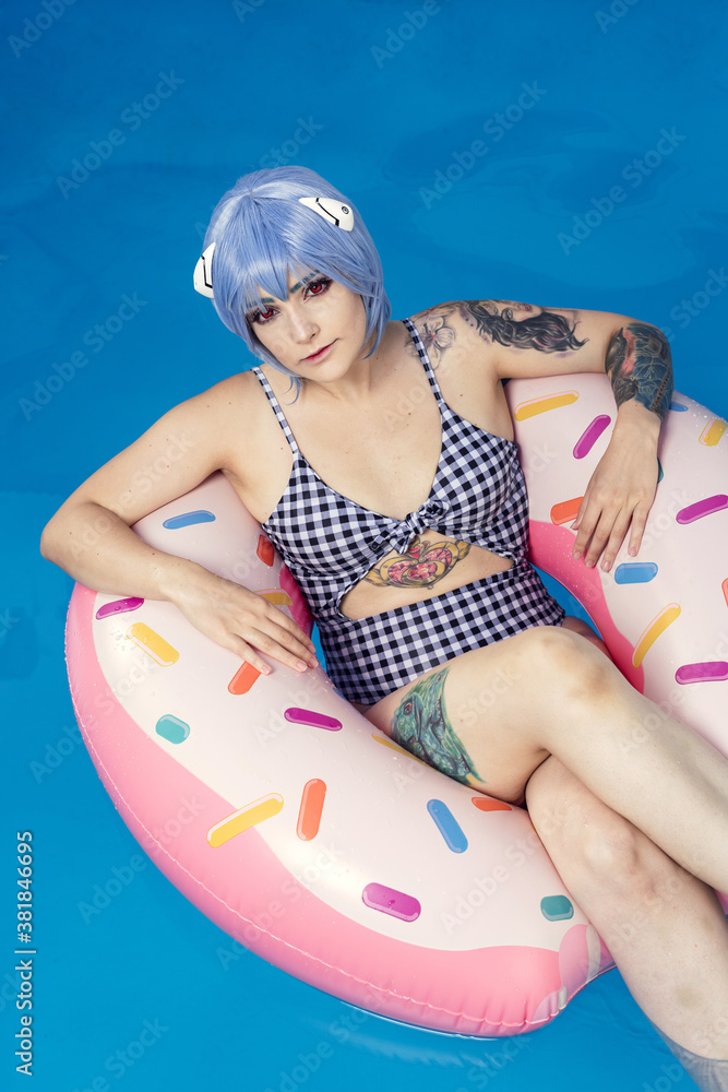 Sticker vertical shot of a european female with blue hair on an inflatable in a pool