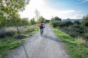 Obraz premium Country road with a cyclist at sunset