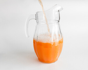 Fresh orange juice is poured into a jug. On white background. Copy space
