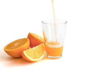 Fresh orange juice is poured into a glass with fresh orange slices cut in half on white background with copy space, top view, banner
