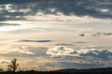 Picturesque landscape, beautiful sky with clouds. In the distance there is a road with city lanterns.