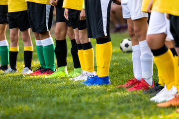 Kids on soccer training. Soccer players standing in a row. Low angle image of footballer's legs in...