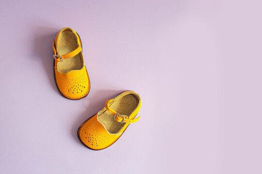 Bright Yellow Kids Shoes On Lilac Background With Copyspace. Baby Clothes Concept. Top View, Flat Lay