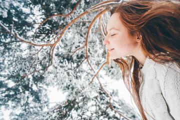 Young smiling woman redhead in a winter forest.