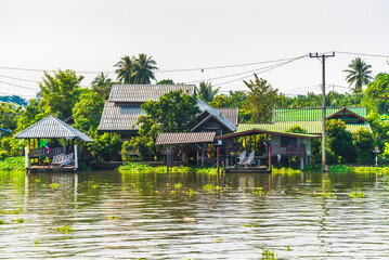 Obraz premium Stilt Houses at a Klong in Bangkok, Thailand. Chao Phraya Riverbank with Lush Vegetation.