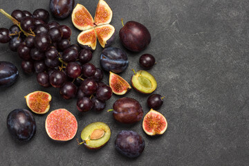 Still life of fruits. Bunch of grapes. Figs and plums. Cut figs, plum halves, plum pits.
