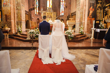 Bride and groom at church wedding during ceremony. Beautiful decoration.
