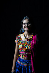 Indian girl in traditional chaniya choli for navratri with a fashionable hairstyle poses in studio...