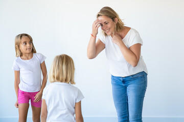 Happy Caucasian mother smiling and talking with children. Beautiful mother and two daughters standing in new house or apartment. White background. Mortgage, relocation and moving day concept