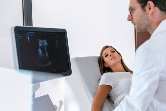 Male doctor doing sonography examination to pregnant female