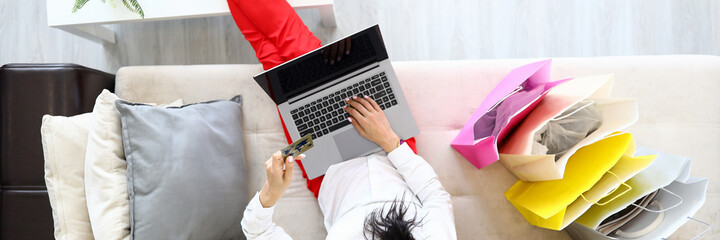 Woman is sitting on couch with laptop and is shopping online. Internet credit card payment concept