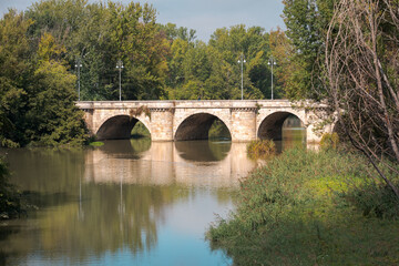Fototapeta na wymiar ashlar stone medieval bridge, puente mayor, crossing rio carrion, in autumn. Palencia, Spain.