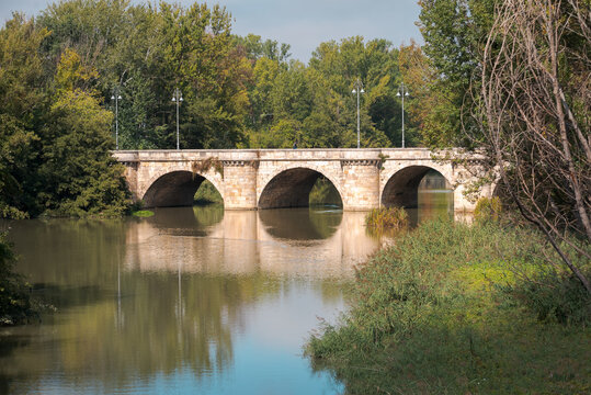 ashlar stone medieval bridge, puente mayor, crossing rio carrion, in autumn. Palencia, Spain.