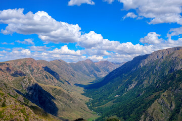 Naklejka premium Mountain gorge landscape with cloudy blue sky. Summer nature landscape. River valley panorama. Kora river gorge in Kazakhstan, way to Burkhan bulak waterfall. Tourism in Kazakhstan concept.