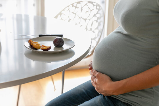 Expecting woman eating fresh fruits at home